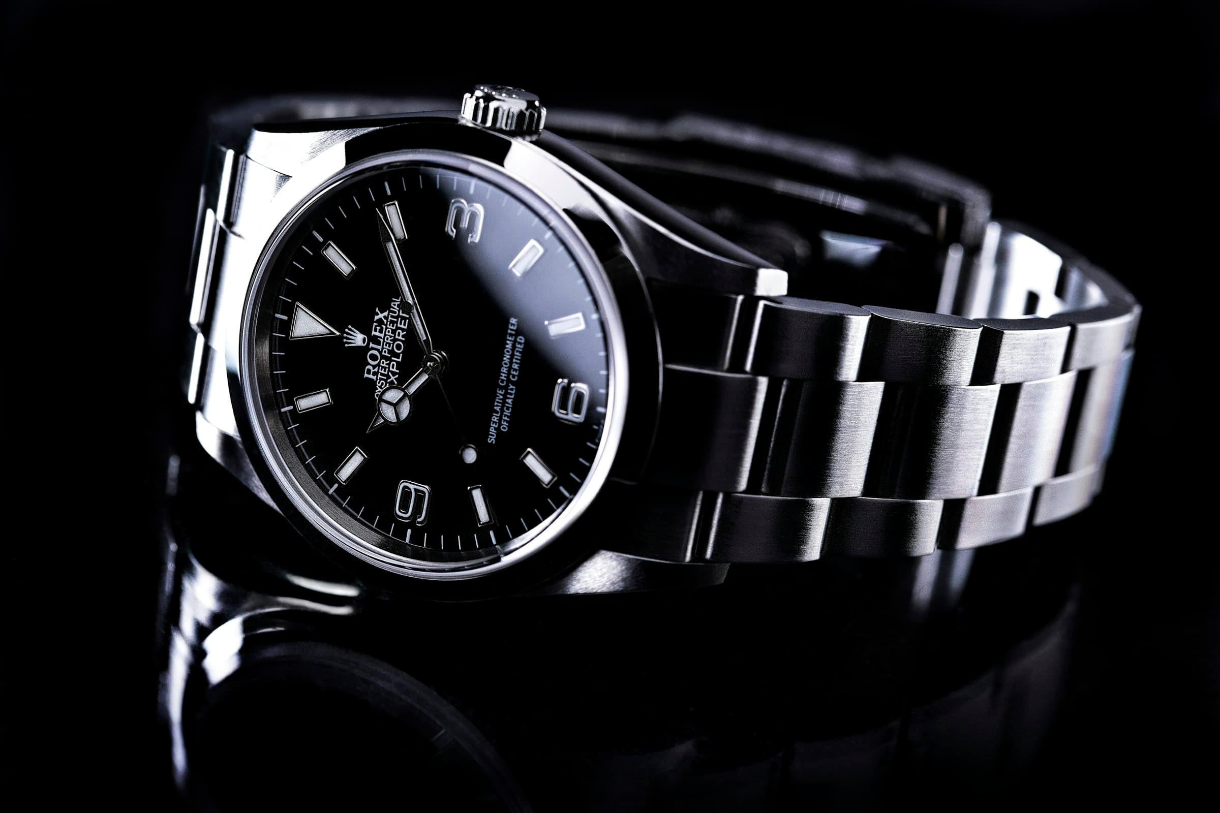 Steel sports watch on a black reflective surface