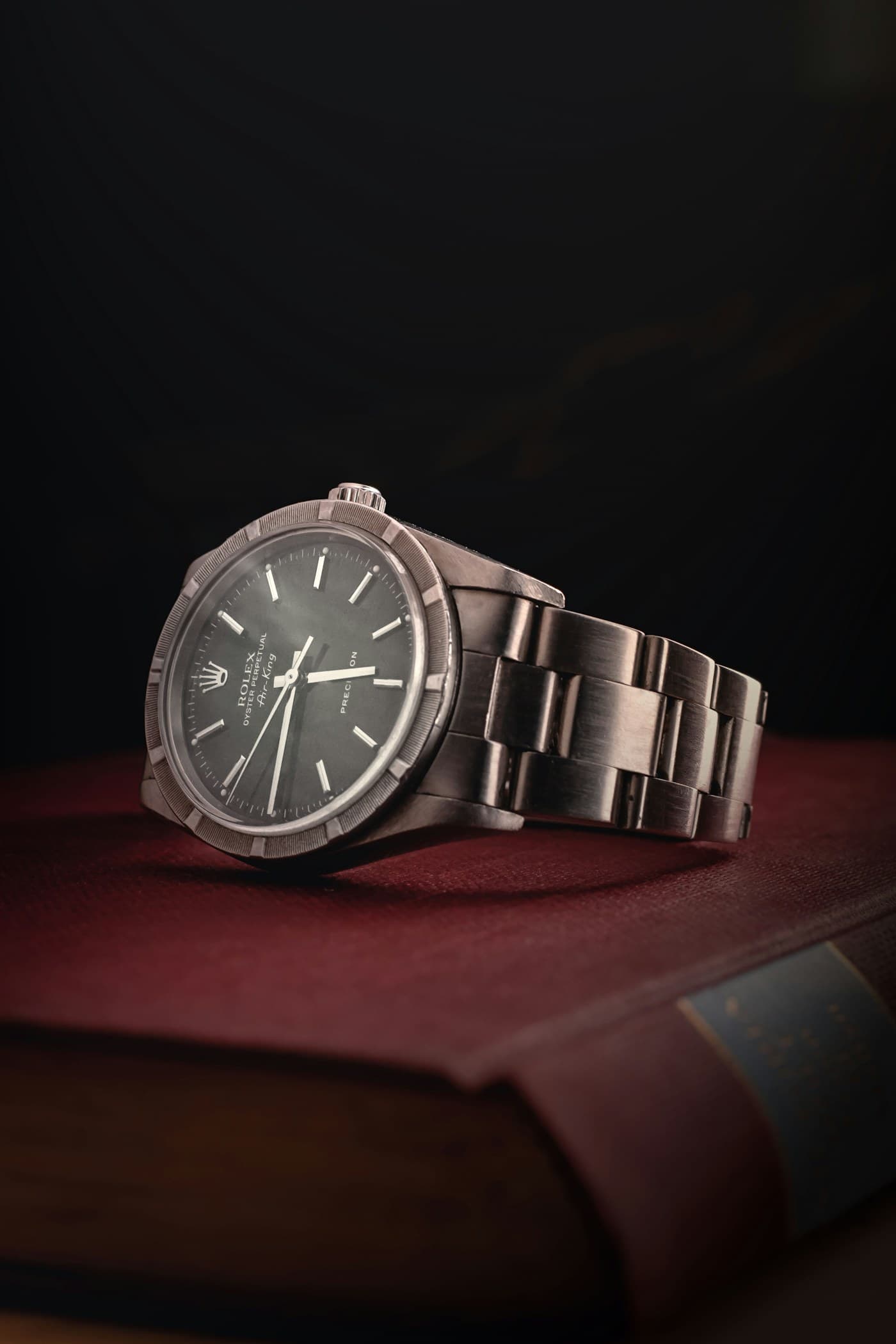Steel watch resting on a red leather-bound book